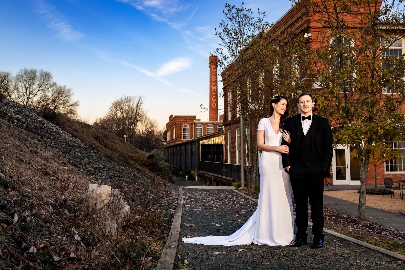 couple in wedding attire poses in front of The Cotton Room and Belt Line Station