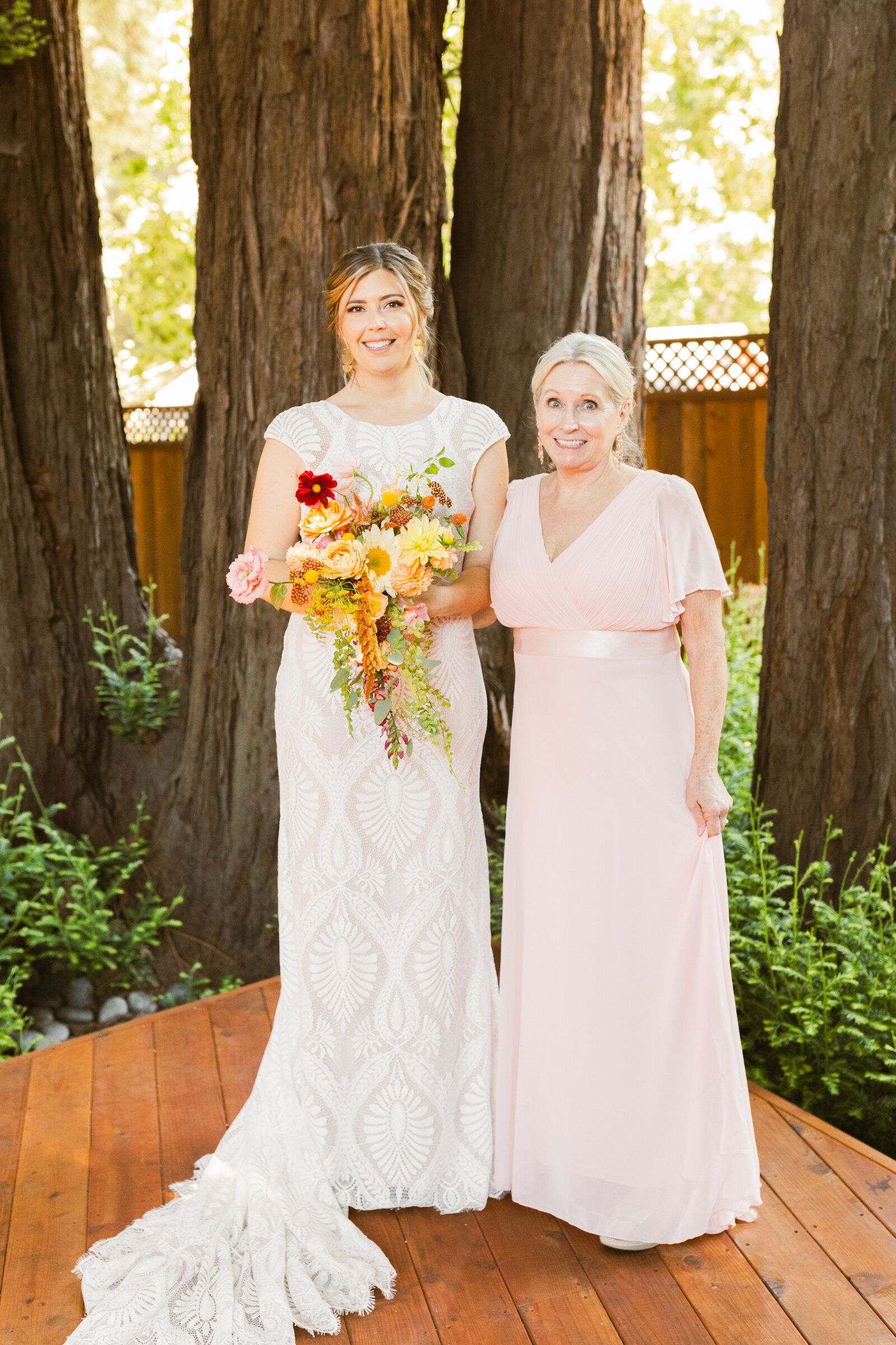 Bride and bridesmaid at her colorful wedding ceremony in Santa Cruz, California in the redwood trees.