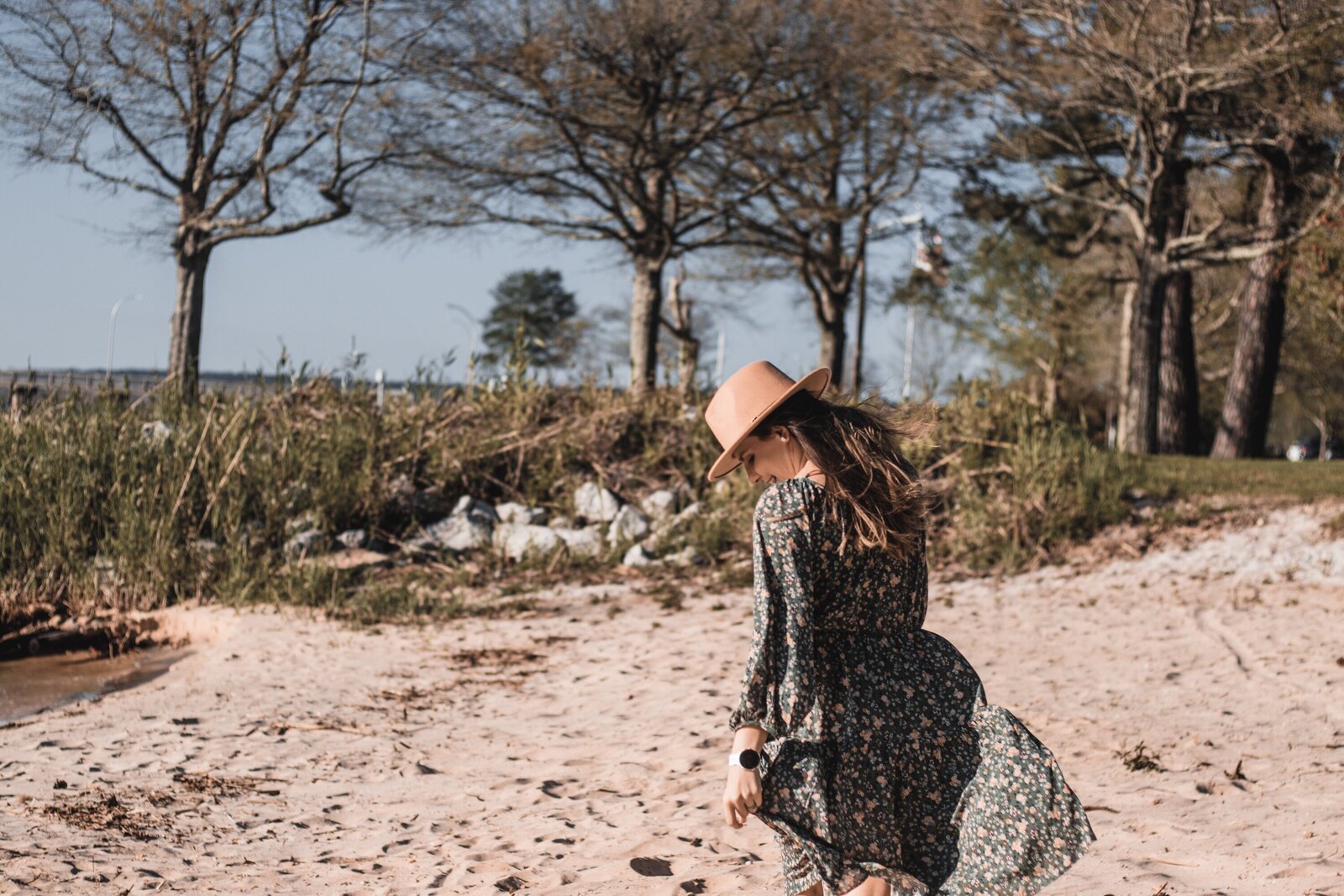 Katelin is wearing a green dress and tan hat while walking away from the camera.