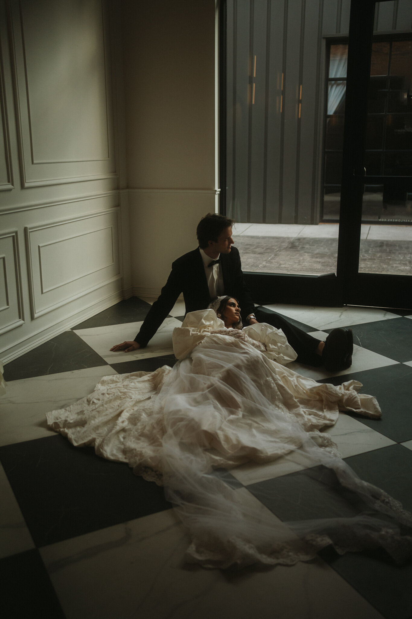 A Nashville wedding couple posed  in an editorial style on a checkerboard marble floor.
