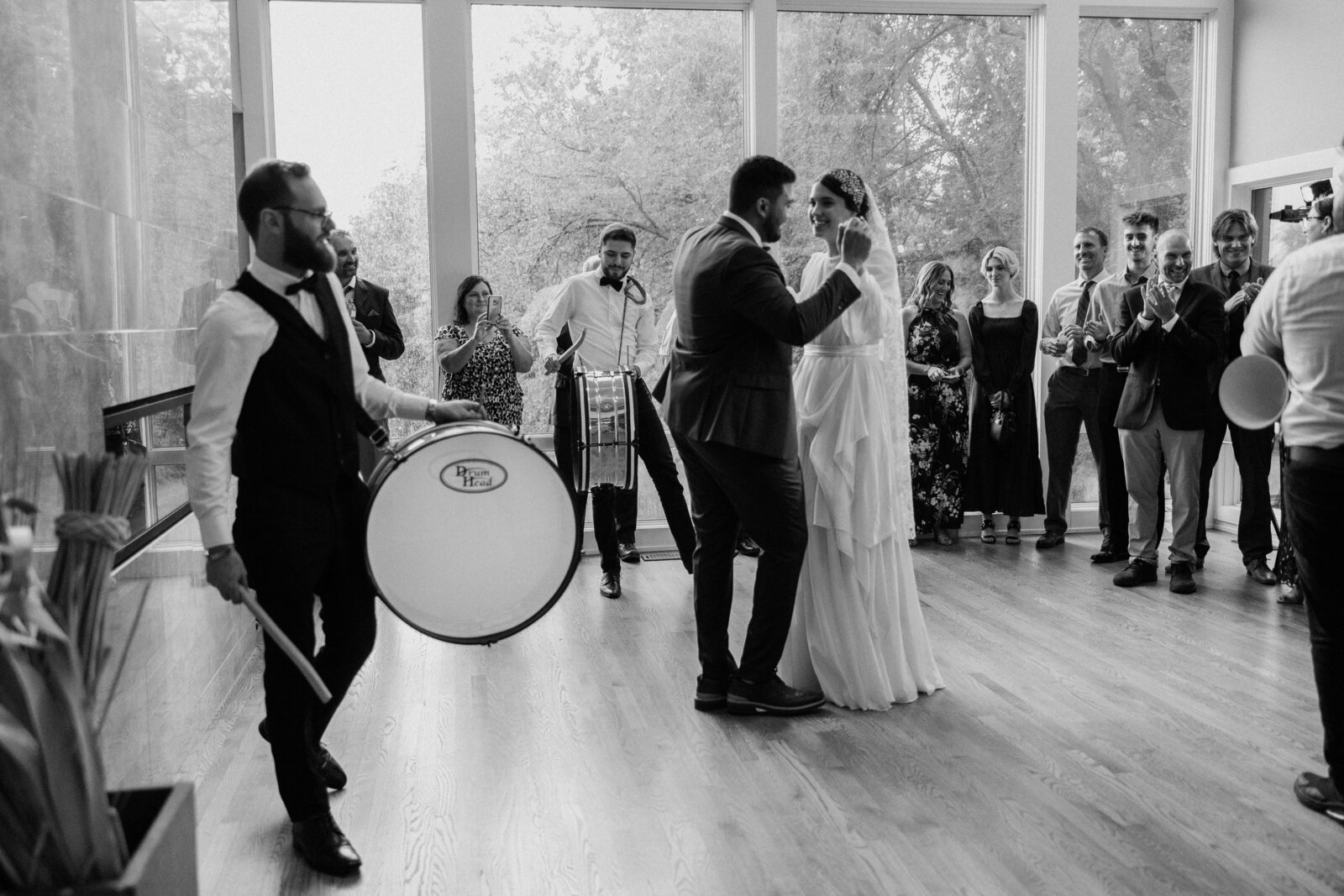 The groom and bride's first dance together, in black and white, as witnessed by their loved ones.