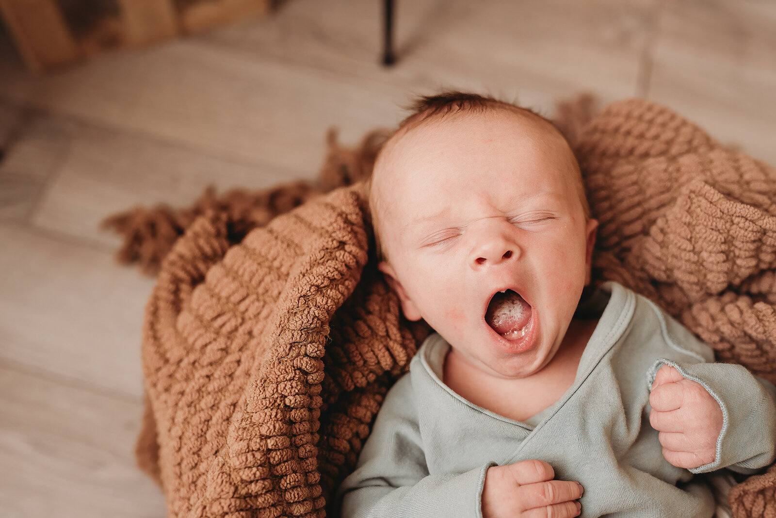 A newborn shows off their little yawns during their newborn photoshoot at Nikii Pix Photography