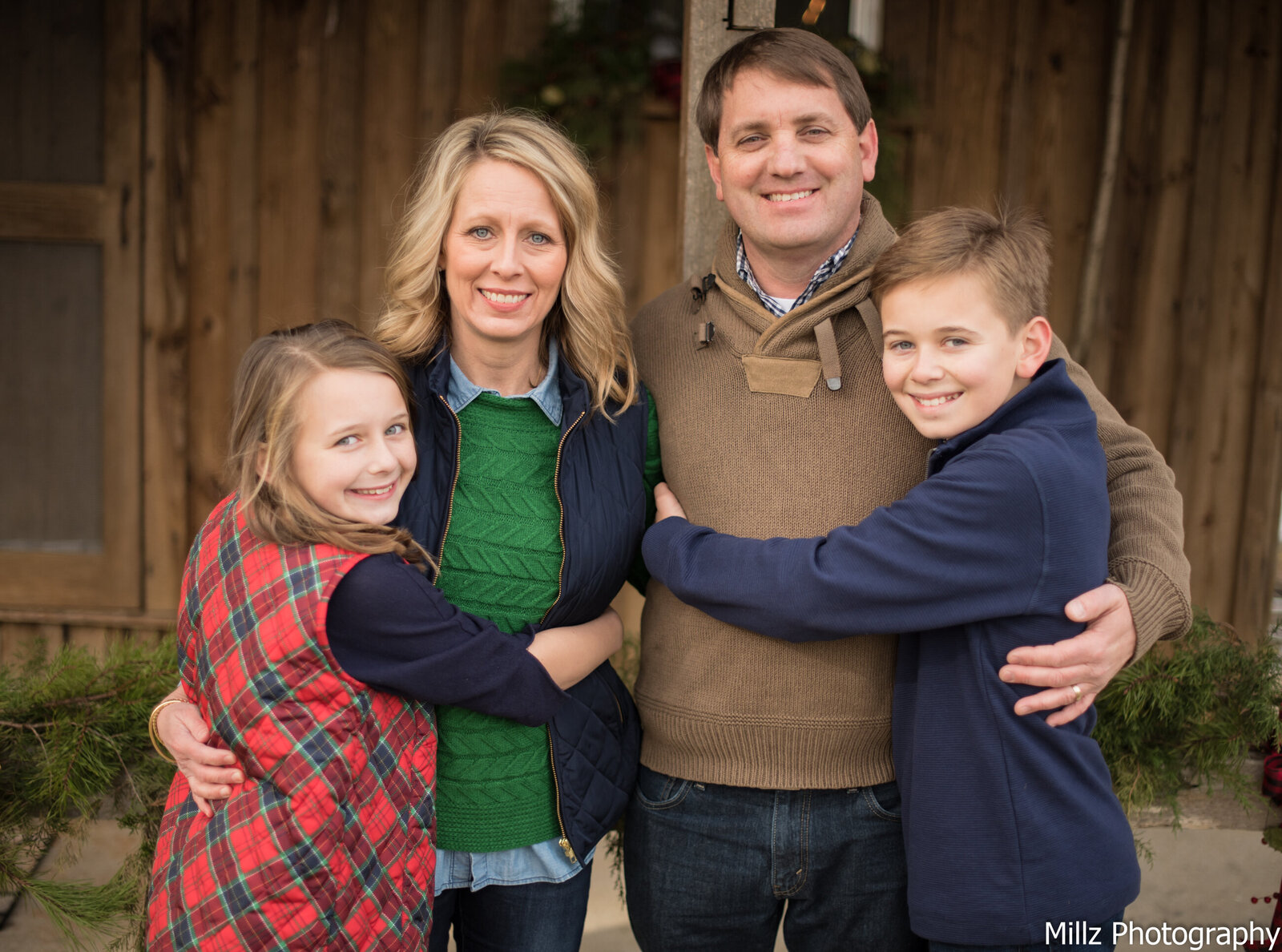 a family of four, father mother son and daughter, embracing each other in a group hug photographed by Millz Photography in Greenville, SC