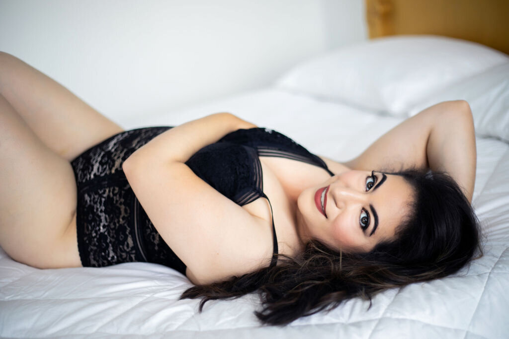 woman lying on back in black lingerie on bed