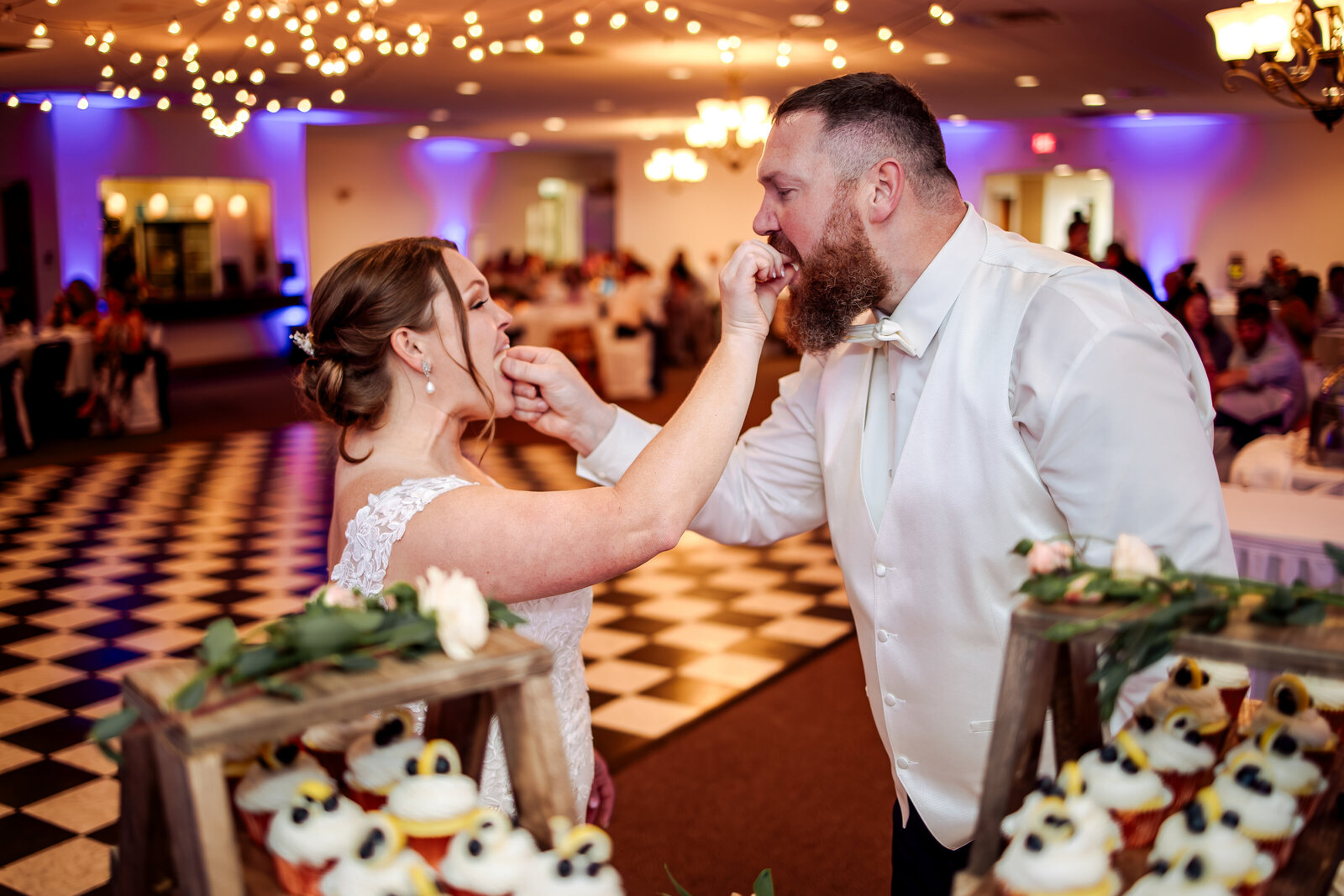Bride and groom feed eachother a piecce of cake at their wedding reception