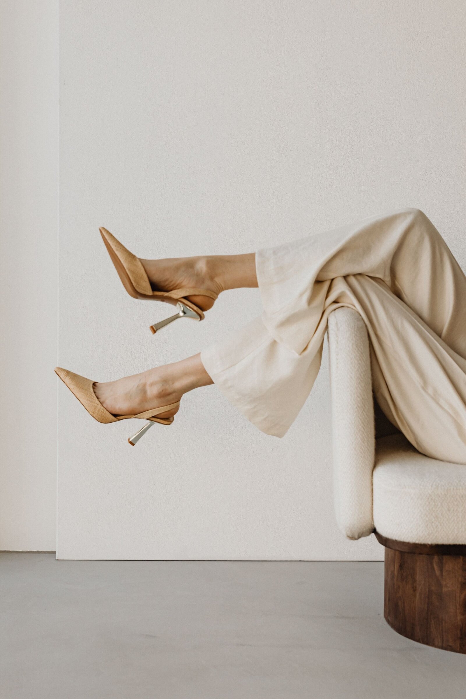 Woman's legs dangling over chair featuring beige stilettos