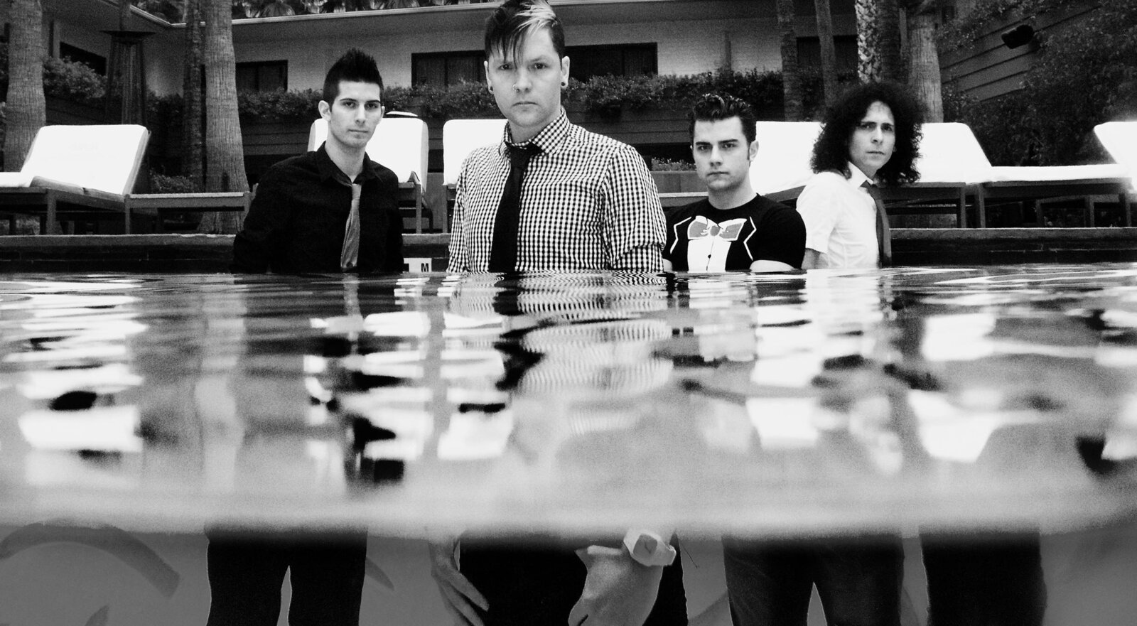Band Photo Hollywood Faber Drive four members standing in pool in full clothing black and white image