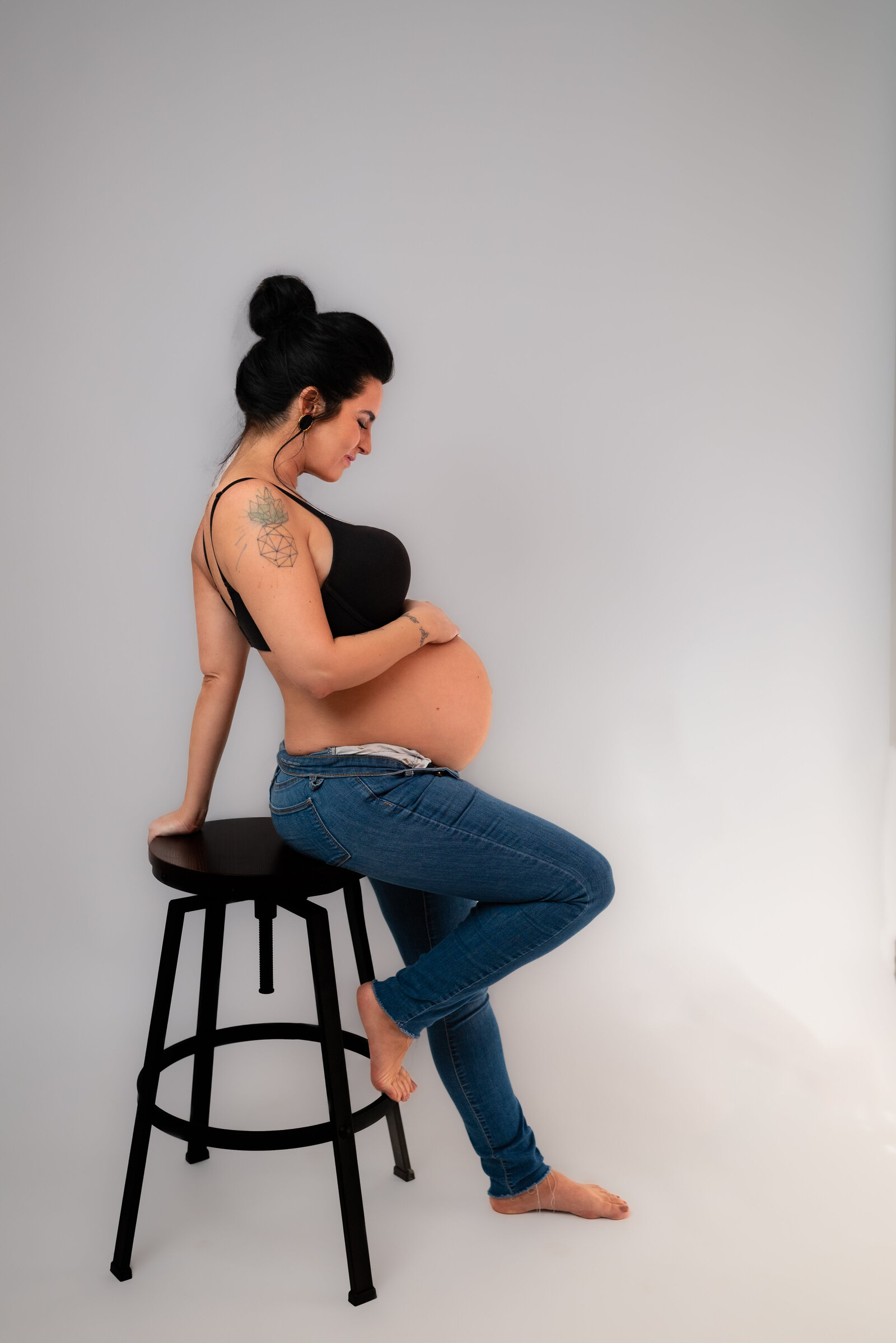 A pregnant woman posing on a stool for her maternity pictures in Huntsville Alabama
