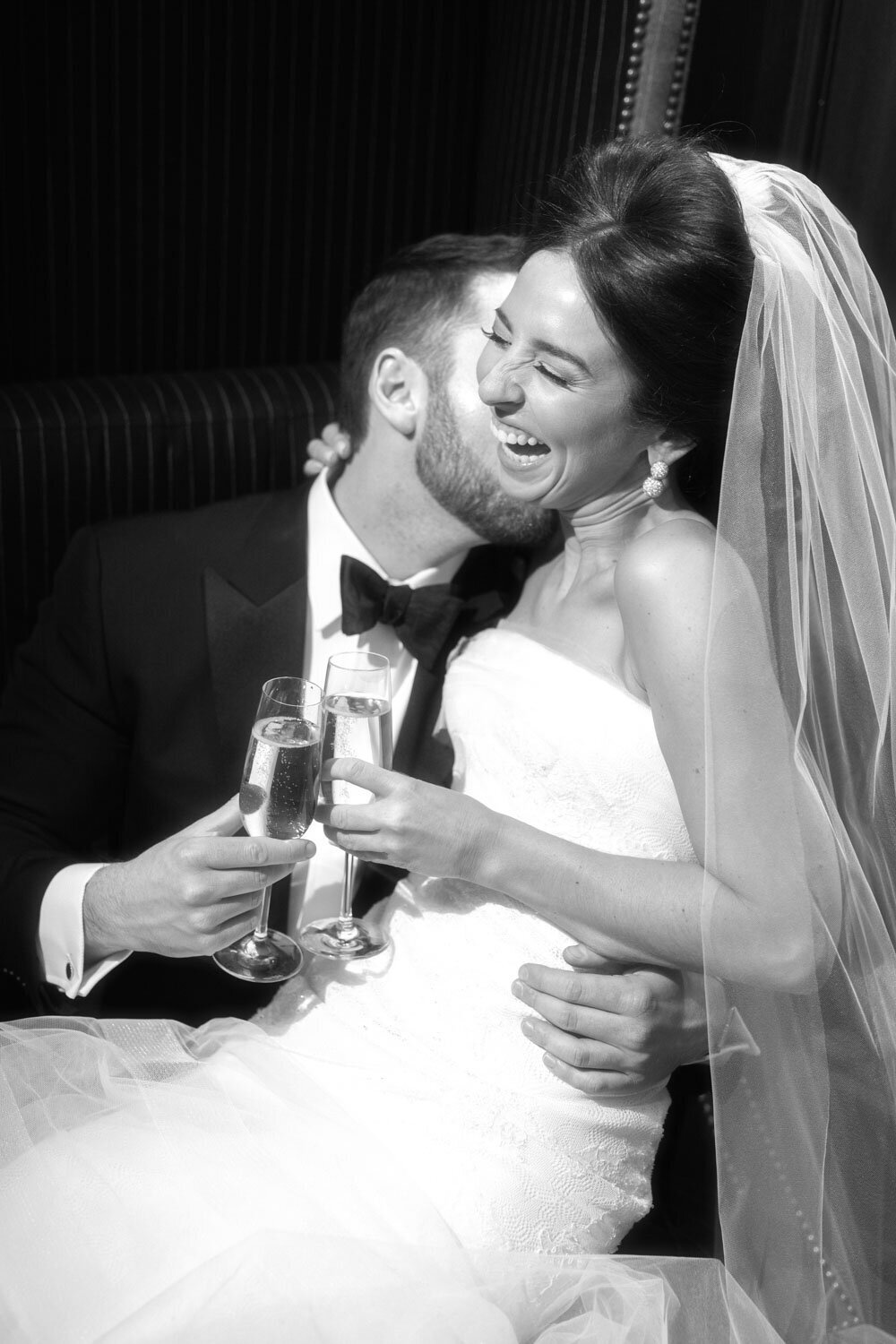 A black and white photo of a bride and groom toasting with champagne