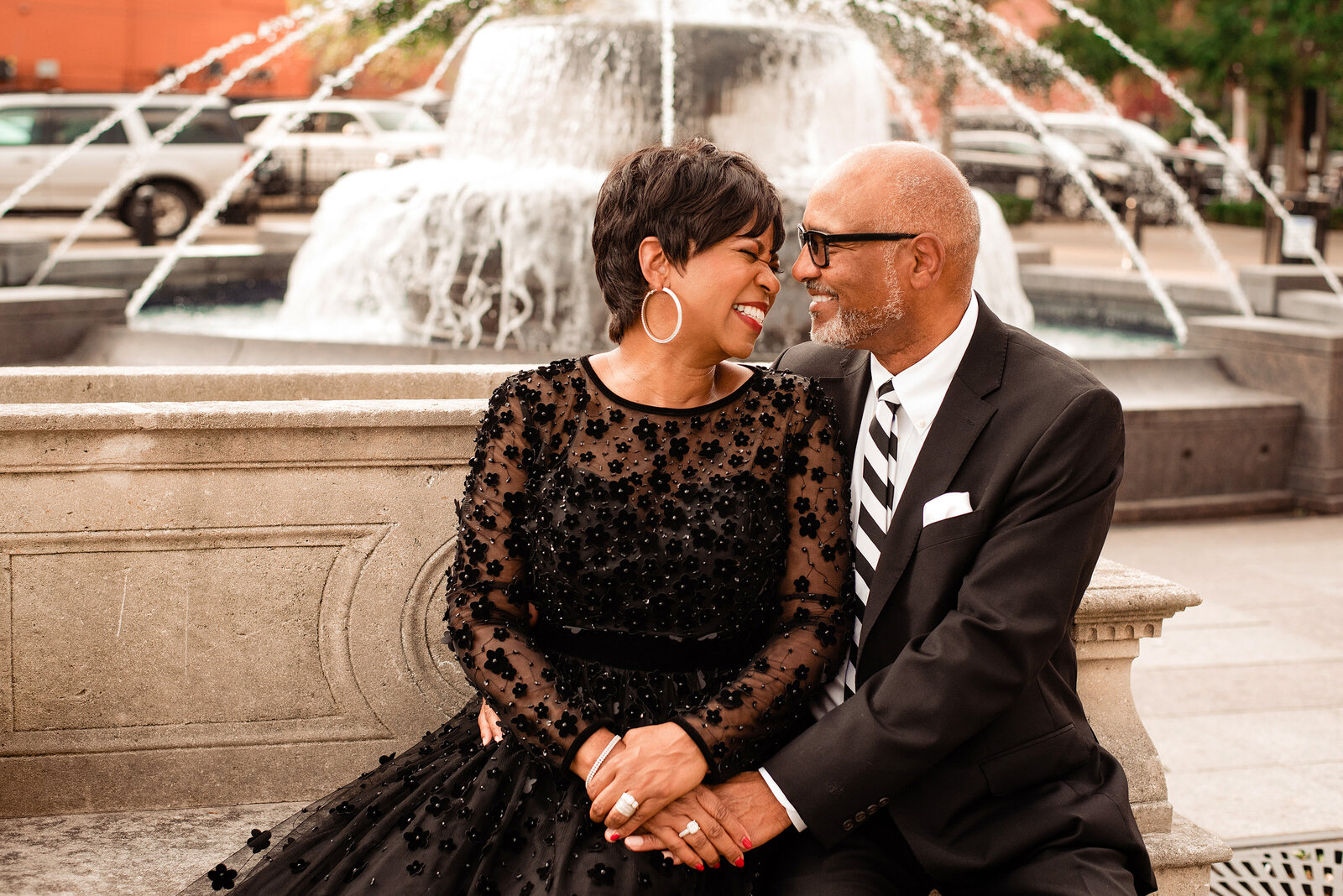 Married couple sitting outside of symphony center smiling at one another in their formal wear with the fountain in the background