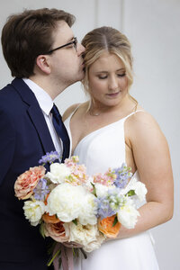 fallback shared on Invalid Date | bride holding a colorful bouquet while groom kisses her on the head