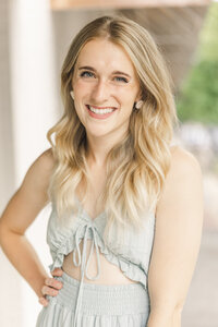 fallback shared on Invalid Date | Shelby smiling in a blue dress with her hand on her hip