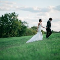 A couple walks up a hill at their wedding in Winchester, Virginia, captured in association with Ashley Cox Photography