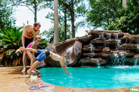A father with his two kids playing at the swimming pool in their backyard