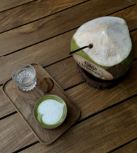 An aesthetic picture of a coconut with a straw in it.