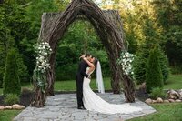 bride and groom kissing underneath a wooden altar