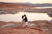 A couple engaged at the Glen Canyon Dam viewpoint, with the expansive views of Lake Powell and the dam in the background.