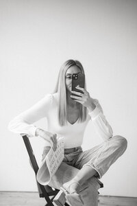 Woman sitting in chair holding cell phone and newspaper, Social Media Agency Branding Photos, Social Media Strategists