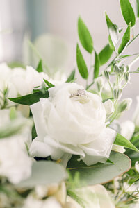 White roses in the bouquet at a wedding with the bride's ring on the top of the petals for a detail shot.