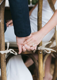 Bride and groom reach for each other’s hands behind rustic ceremony chairs—intimate moment at The Westin Savannah Harbor Resort wedding, captured by luxury wedding photographer Amia Marcell.