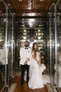 Bride and groom stand in cellar where their reception is hosted for family-oriented wedding | Sush Digital Media
