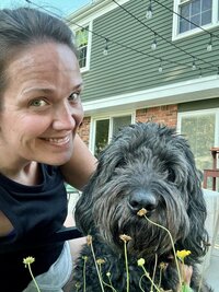 Testimonial photo of Amber taking a selfie with her black Newfypoo for Dogology University
