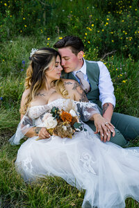 Jaw dropping same sex couple posing naturally in the flowers in the grass. Ideas for wedding poses sitting.