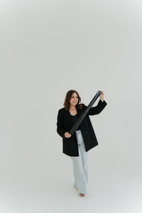 Photographer holding a film strip while smiling in a minimal studio setting.