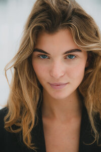 Natural close-up portrait of a woman with wavy hair, shot by Bo Eppink for a  campaign, showcasing minimalistic beauty and fashion.