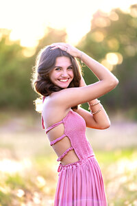 Beautiful golden hour sunset senior photos in Winter Garden, FL. Senior Girl is wearing pink dress with dark hair and smiling at the camera.