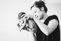 Geboortefotografie - Vroedvrouw houdt baby vast zoals baby net nog in de buik zat
