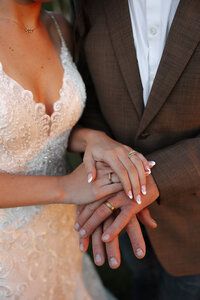 A couple stacking their hands together during a engagement session, with their rings prominently displayed, capturing a moment of love and commitment
