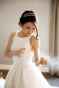 Bride spraying perfume on her hands