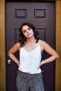 Blue eyed brunette girl wearing a white cami in front of a purple door on Historic Commercial Street. Captured by Springfield, MO photographer Dynae Levingston.
