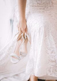 A bride sitting with her bridal shoes, preparing for her New York wedding with Most Valuable Bridesmaid day-of coordination team by her side.