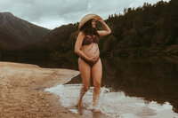 Traveling family photographer, pregnant woman walking along the edge of a lake