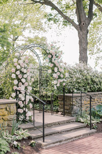 Steps with black railings leading up to a rose arbor