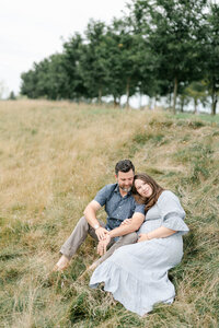 Philly couple cuddles in a field during maternity session with AnneMarie Hamant