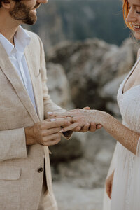 groom placing ring onto brides finger