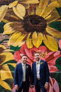 LGBTQ couple in front of flower mural