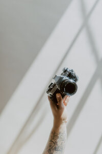 Wedding Photographer Jessica Cameron holds her camera next to a glass of champagne