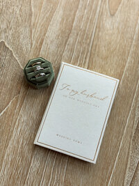 Wedding invitation with a green ring box with rings on a wooden background