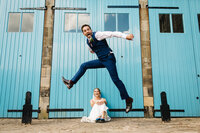 groom doing the mid air splits as his bride watches on