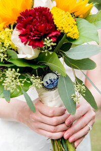 red and yellow bridal bouquet with greenery and portrait of grandparents