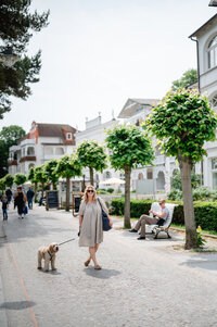 Frau geht mit Hund an der Binzer Promenade spazieren.