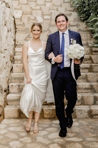 A bride and groom walk hand-in-hand down a stone staircase, capturing the elegance of a destination wedding. Destined’s expert team specializes in creating bespoke wedding experiences in breathtaking destinations worldwide.