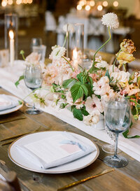 plates and flowers and dishes on large wooden table at wedding reception