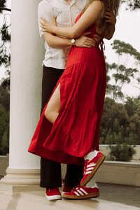 woman standing next to partner, wearing red dress and red adidas sneakers