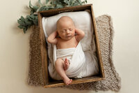 Posed newborn laying in a crate