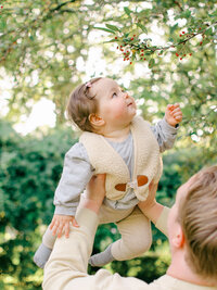 Father lifts baby girl in an Amsterdam park.